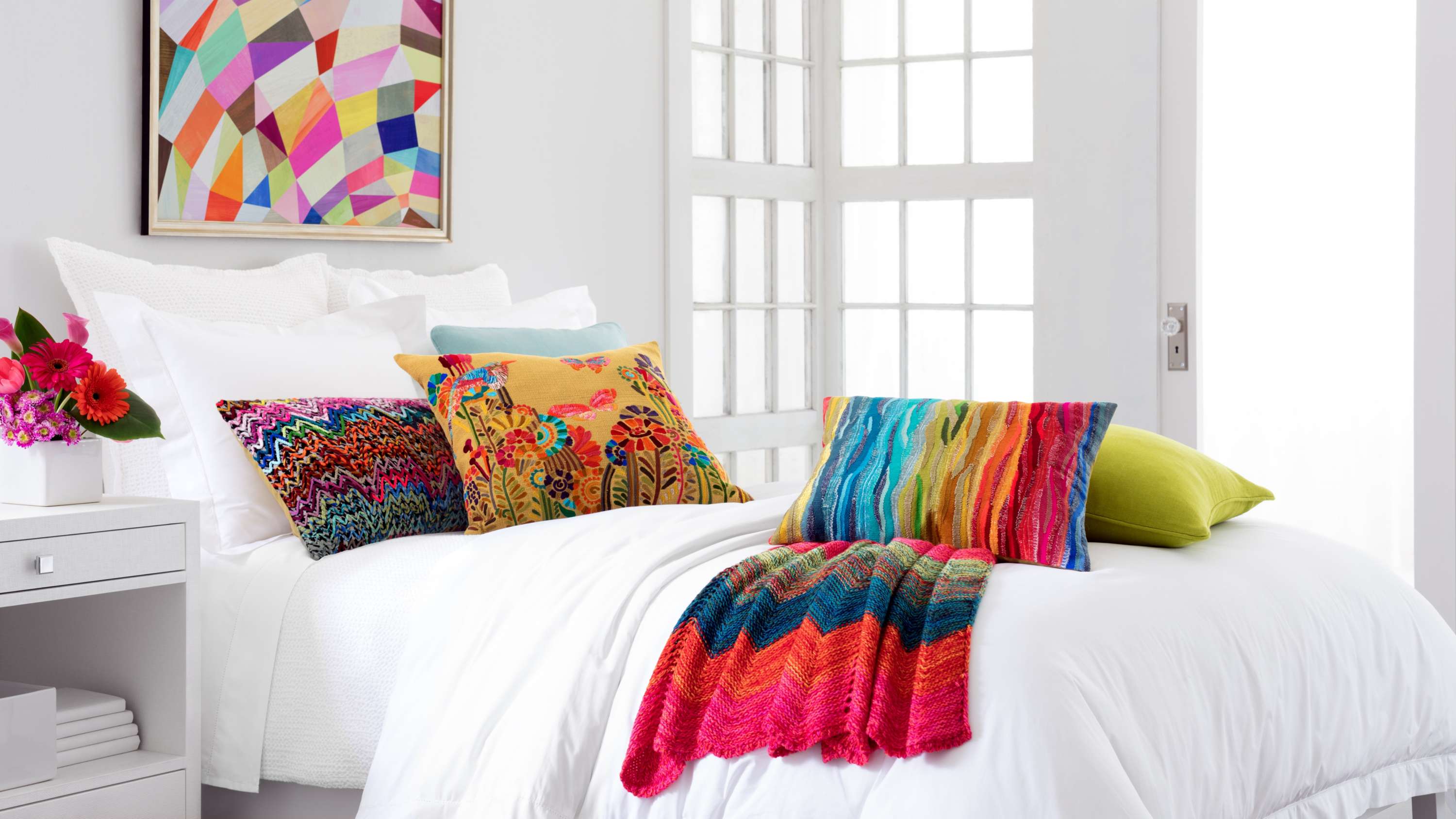 white bedspread with colorful pillows